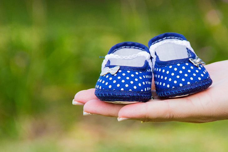 pair of blue crib shoes on top of person's hand