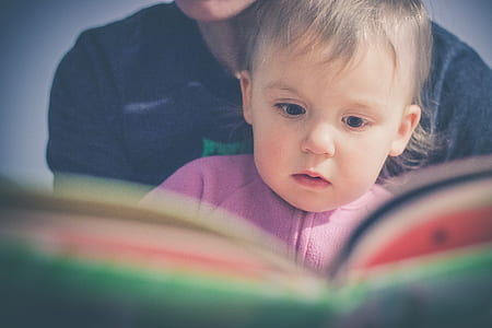 baby in purple shirt reading book