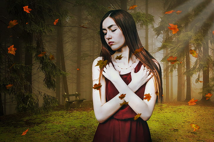 woman wearing red dress standing with falling leaves at forest