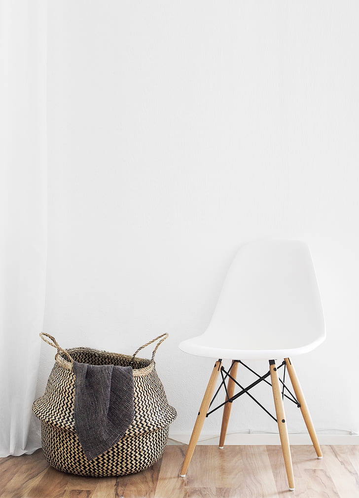 white and brown chair beside fabric clothes basket