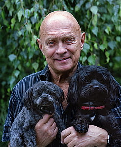 man in black pinstriped shirt carrying puppies