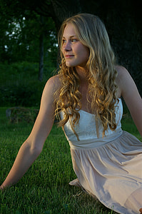 woman wearing white and beige floral dress sitting on green grass field
