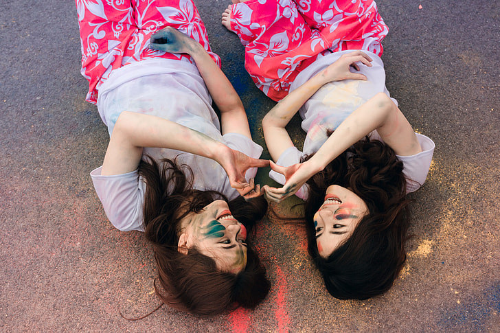 two women laying on floor doing heart sign together