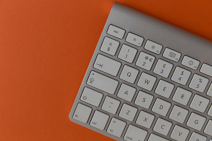 Apple wireless computer keyboard on orange background