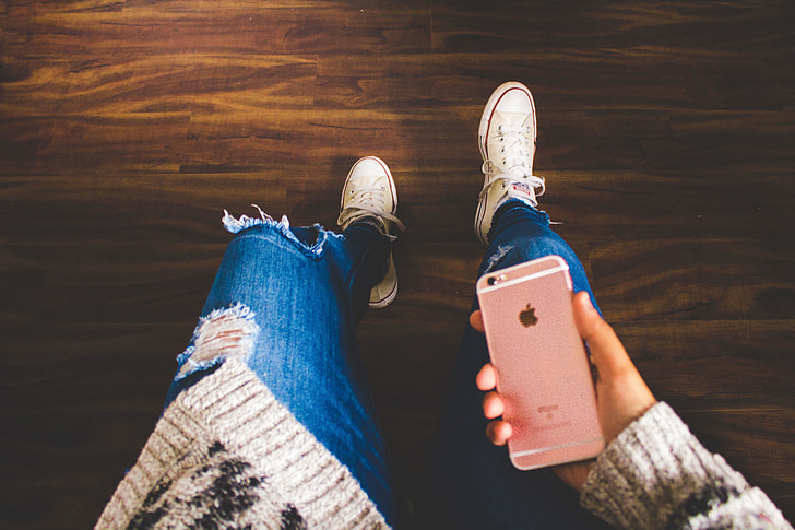 A girl wearing jeans looking down at her mobile iPhone smartphone