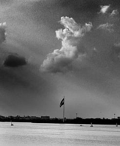 Grayscale Photo of Flag and Clouds