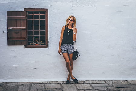 woman in black sleeveless top standing in front of white wall