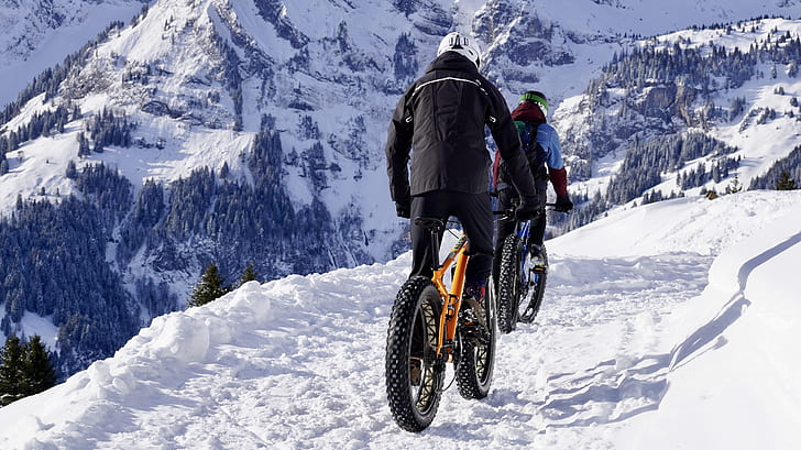 man riding yellow fat bike on snow-covered road