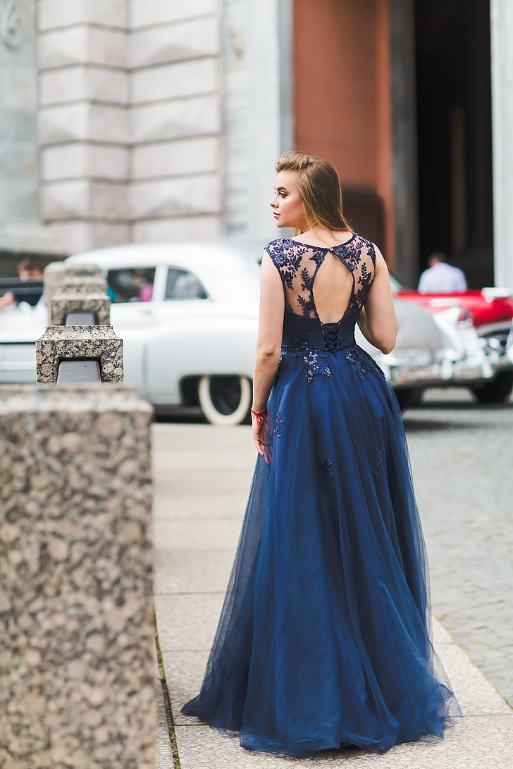 woman wearing blue dress standing on pavement