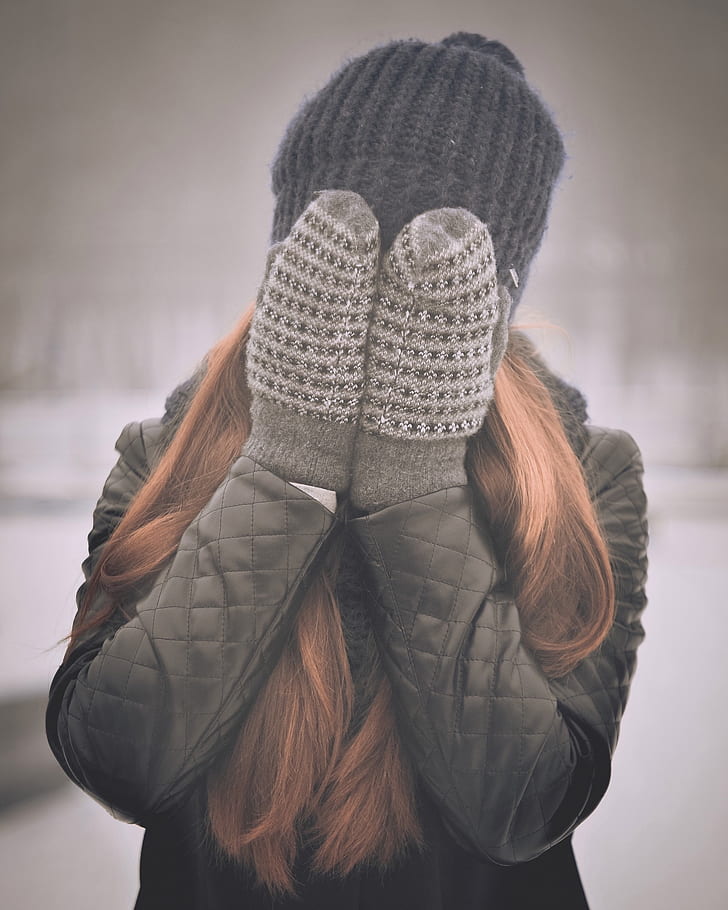 woman covering her face wearing winter gloves