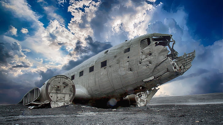 wrecked airplane under blue sky and white clouds during daytime