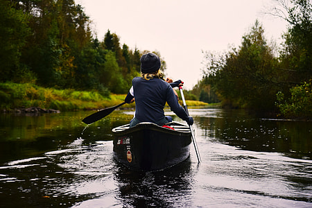 person in black long-sleeve shirt riding black canoe during daytime