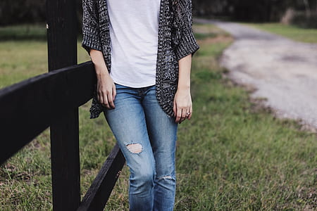 person wearing black cardigan and distressed blue denim jeans