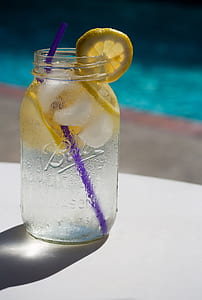 selective focus photography of clear glass mason jar with lemonade and purple straw