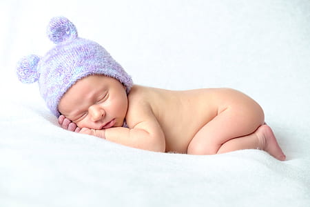 baby sleeping while wearing purple knit cap