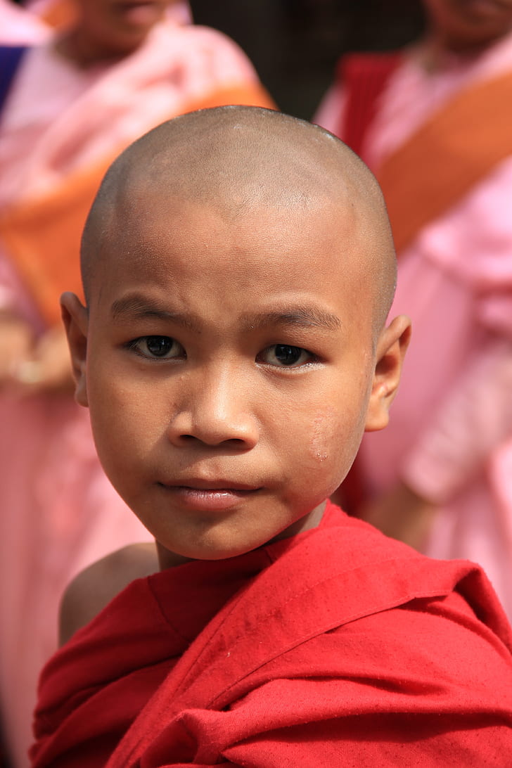 selective focus photography of boy in red monk dress
