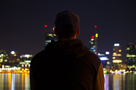 A man sitting at night looking at the city lights