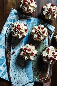 six cupcake with pomegranate toppings on brown tabletop