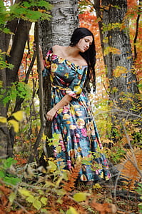 woman wearing blue and yellow floral off-shoulder maxi dress standing beside green tree