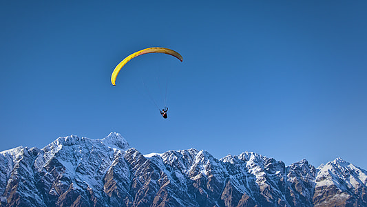 person wearing yellow paragliding with background of mountain