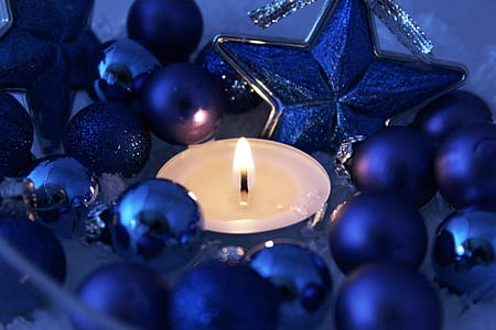 close up photography of lighted tealight candle surrounded with blue baubles