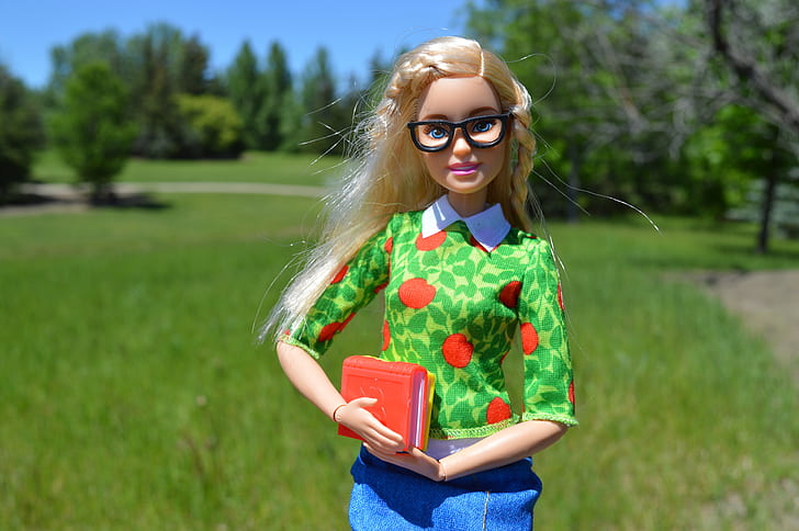 barbie doll action figure in front of green grass field