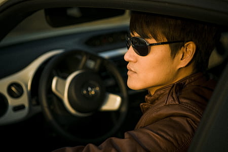 man wearing brown leather jacket inside car