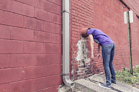 person wearing purple shirt and blue-washed jean inserting inside the wall