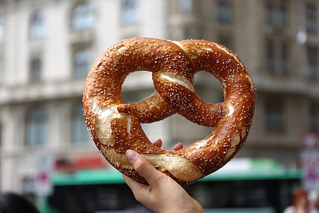 shallow focus photography of person holding pretzel