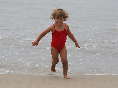 girl wearing red swimsuit on seashore