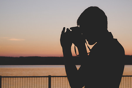 silhouette of a man taking pictures during sunset
