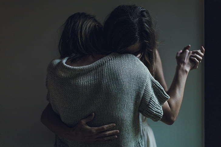 two person hugging in front of white painted wall