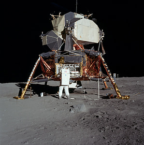 standing astronaut beside gray and brown spacecraft