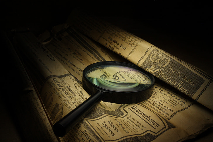 photography of magnifying glass on printed brown paper