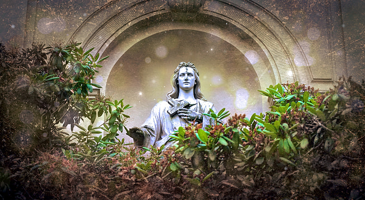 photo of gray statue surrounded by green plants