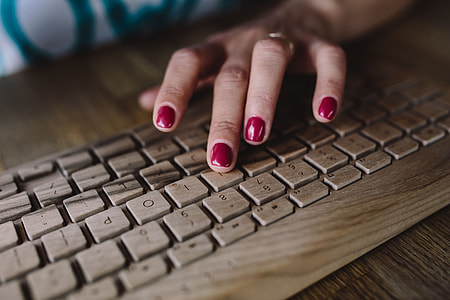 Closeup of female hands typing text on a wireless wooden keyboard