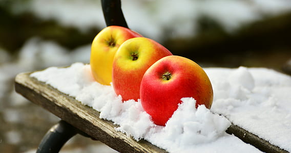 selective focus photography of three red apples on table covered with snow