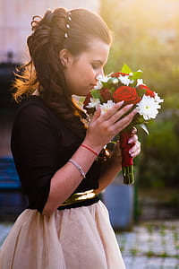 shallow focus photography of a woman holding bouquet of white and red flowers