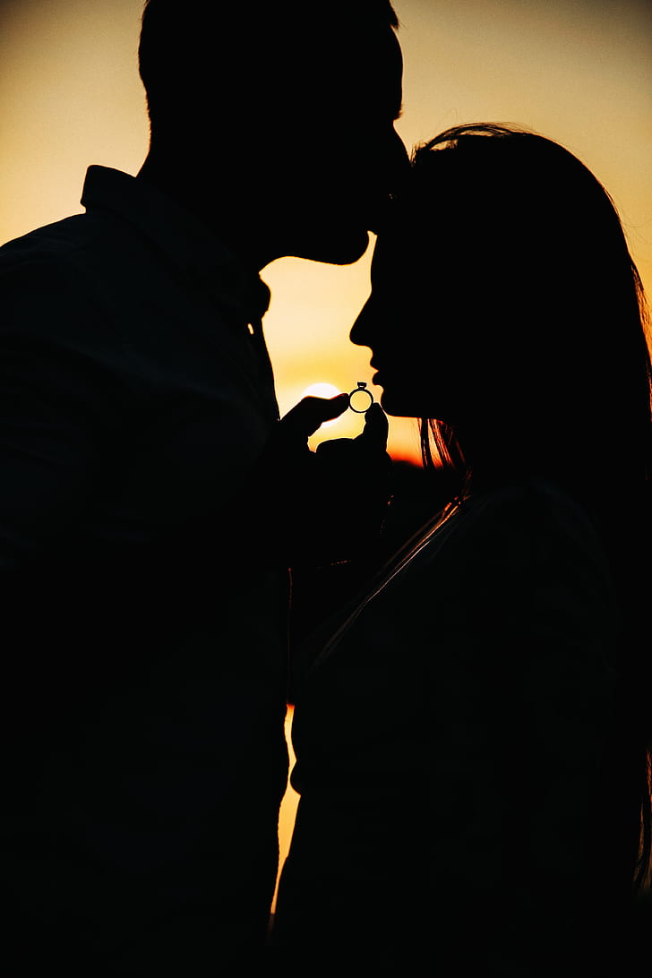 silhouette of couple holding ring during golden hour