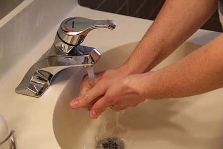 person washing hands on faucet