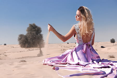 woman wearing purple dress playing with sand