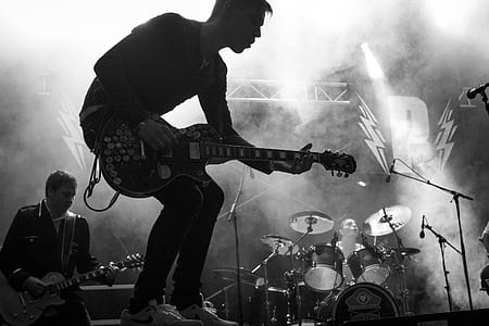 grayscale photo of man playing guitar in stage