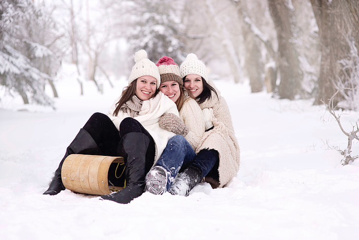 three women sitting on sled at daytime