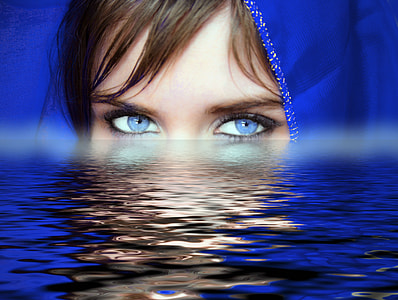 woman with blue eye lens and head scarf on body of water