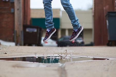 person in sneakers jumping on a water on the street
