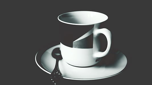 White and Black Ceramic Tea Mug on White Ceramic Round Plate and Stainless Steel Spoon on Top