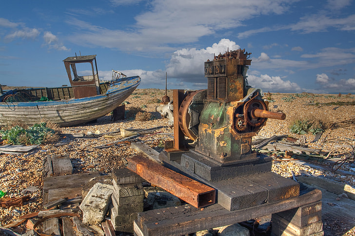 An abandoned boat and engine lie on the coast at Dungeness, Kent, England
