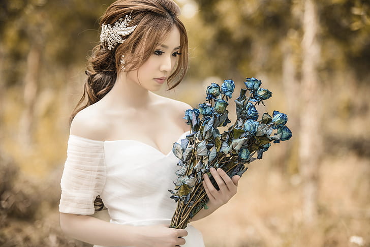 woman in white cold-shoulder dress holding blue flower bouquet