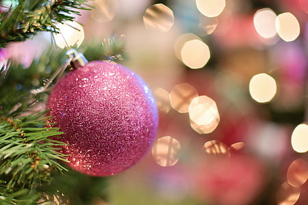 pink glitter Christmas bauble with bokeh background in selective-focus photography