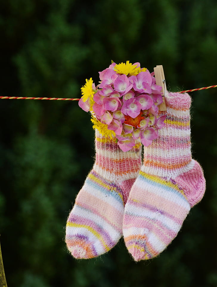 shallow focus photo of pair of multicolored socks hanging on red and yellow rope